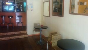 A bar area with stools, a small table, and a mirror on the wall. - Ben Yehuda Hotel (Tel Aviv)
