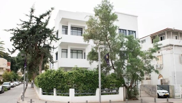 A modern white building with a flat roof, surrounded by trees and parked cars. - Ben Yehuda Hotel (Tel Aviv)