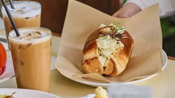 Ein Tisch mit einem Sandwich, Eisgetränken, einem Teller mit Toast und einer kleinen Schale Butter.