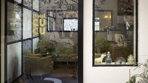 Ein Hotelzimmer mit modernem Design, ausgestattet mit einer Couch, einem kleinen Tisch und Dekoration auf einem Regal.