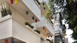Ein Café mit Außenbereich, einem Balkon mit hängenden Pflanzen und einem sichtbaren Restaurantschild.