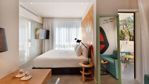 Ein modernes Hotelzimmer mit Bett, Schreibtisch, Stuhl, Fernseher und Blick ins Freie.