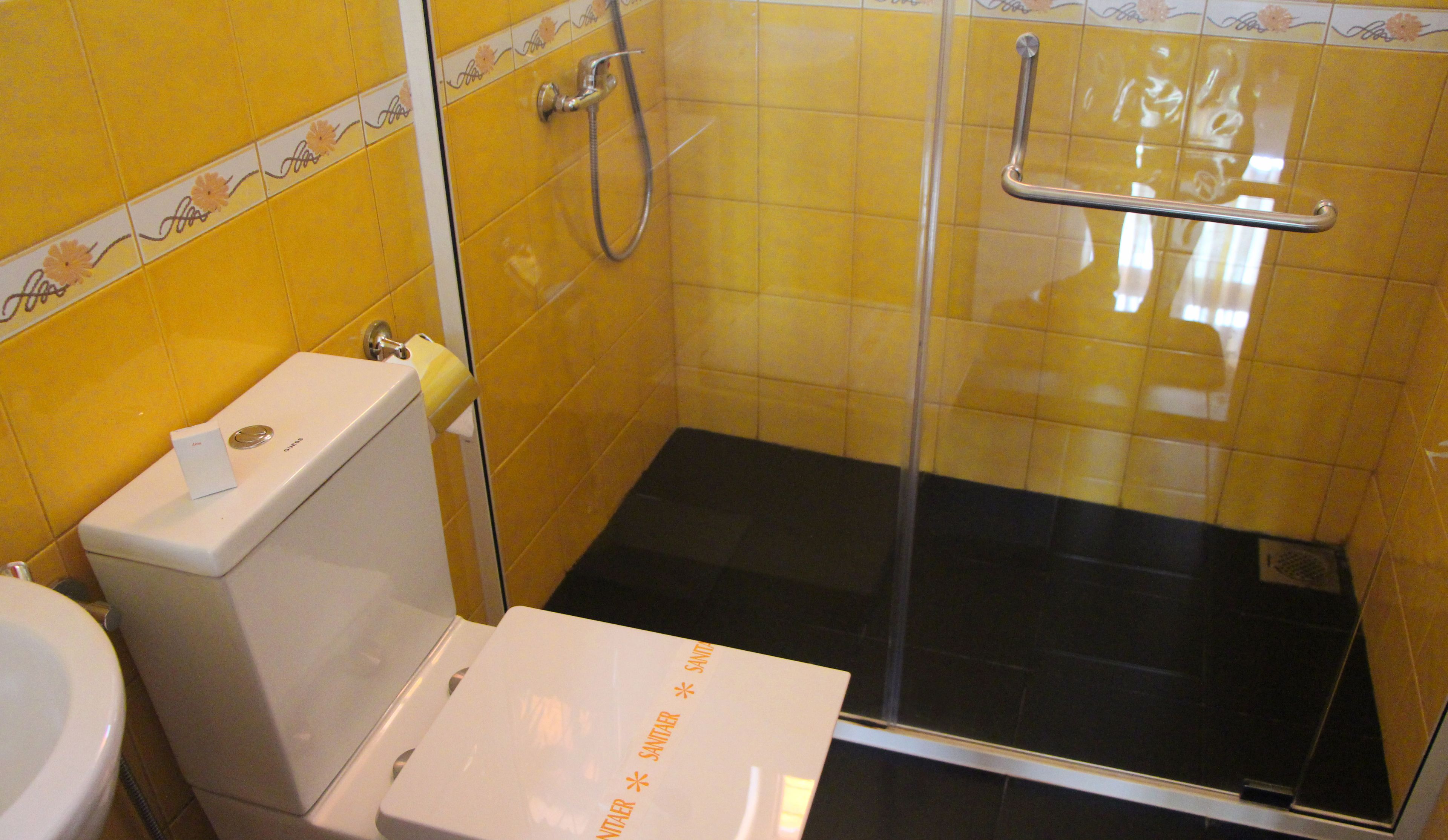 A small bathroom with a toilet, a shower with a glass door, and a sink.
