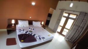 Una habitación de hotel con una cama grande, dos mesitas de noche con lámparas, una ventana con cortinas y vistas al exterior.