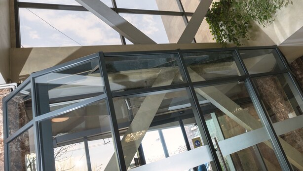 A modern interior with a glass elevator shaft, large windows, and a green plant wall. - Ani Central Inn (Yerevan)