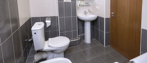 A modern bathroom with a toilet, sink, and bidet.