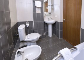 Een moderne badkamer met toilet, wastafel en hygiëneschuimer.