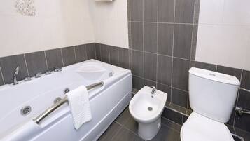 A bathroom with a bathtub, bidet, and toilet.