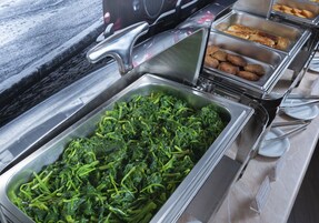 Een buffet met diverse gerechten, waaronder groenten, brood en vlees.