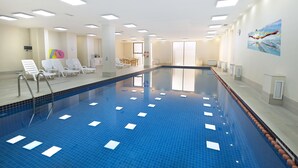 An indoor swimming pool with clear lanes, lounge chairs, and a lifeguard chair. - Ani Central Inn (Yerevan)