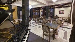 A grand lobby with a grand piano, elegant dining tables, and chairs, and a chandelier. - Ani Central Inn (Yerevan)