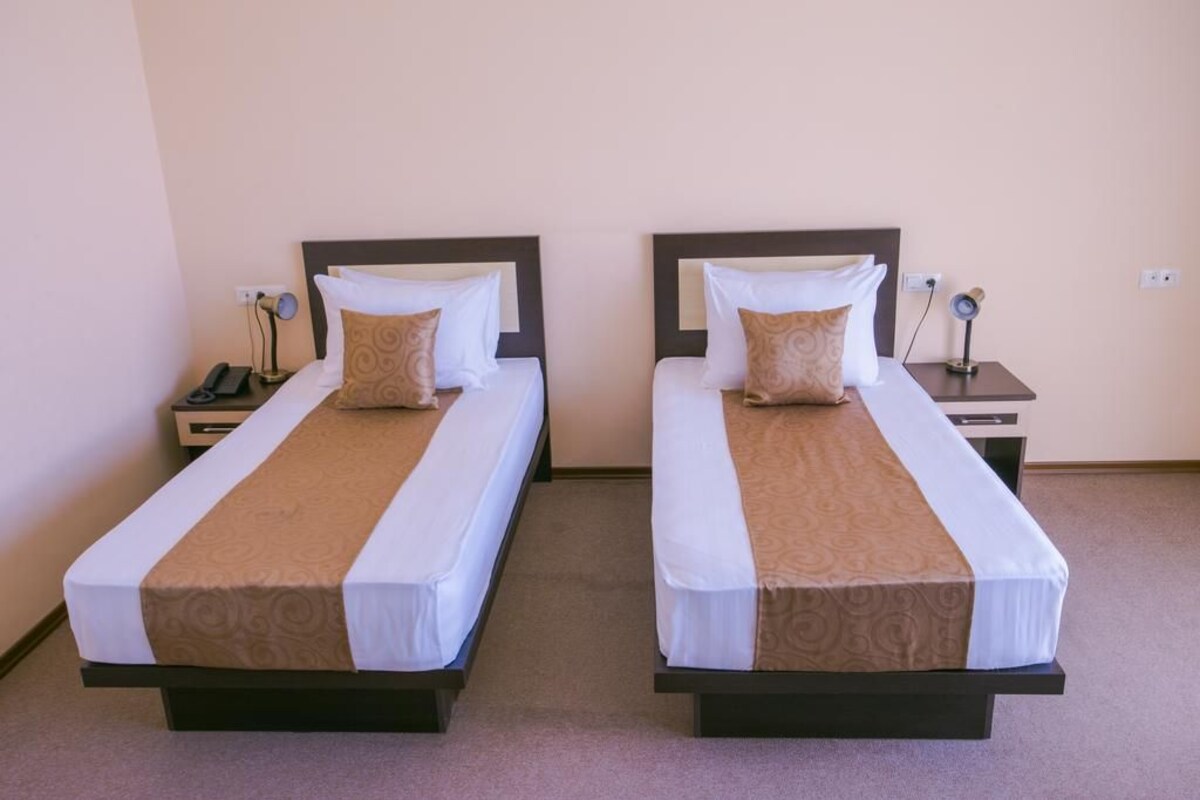 Two single beds with headboards, bedside tables, and lamps.