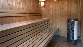 Una sauna de madera con bancos y una unidad de calefacción central.
