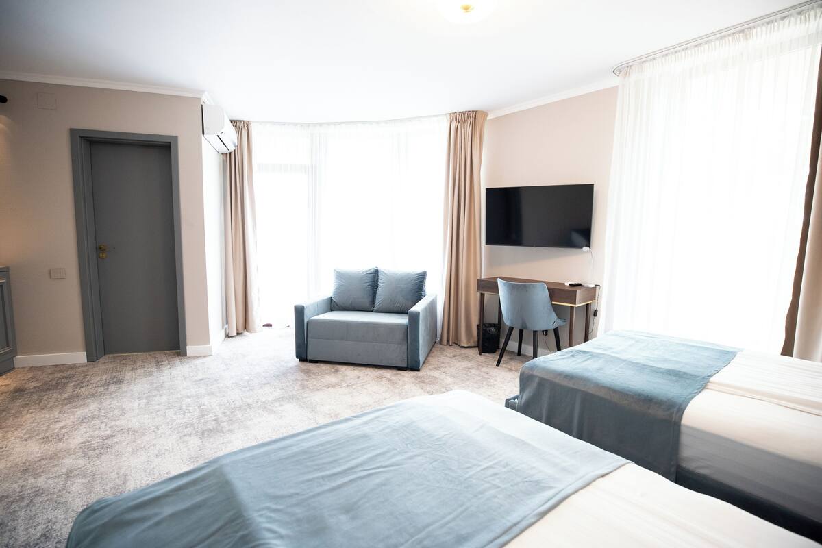 Una habitación de hotel con dos camas, un escritorio, una silla y un televisor.