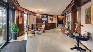 A spacious lobby with a reception desk, comfortable seating, and a large potted plant. - Hotel Meridian (Cluj-Napoca)