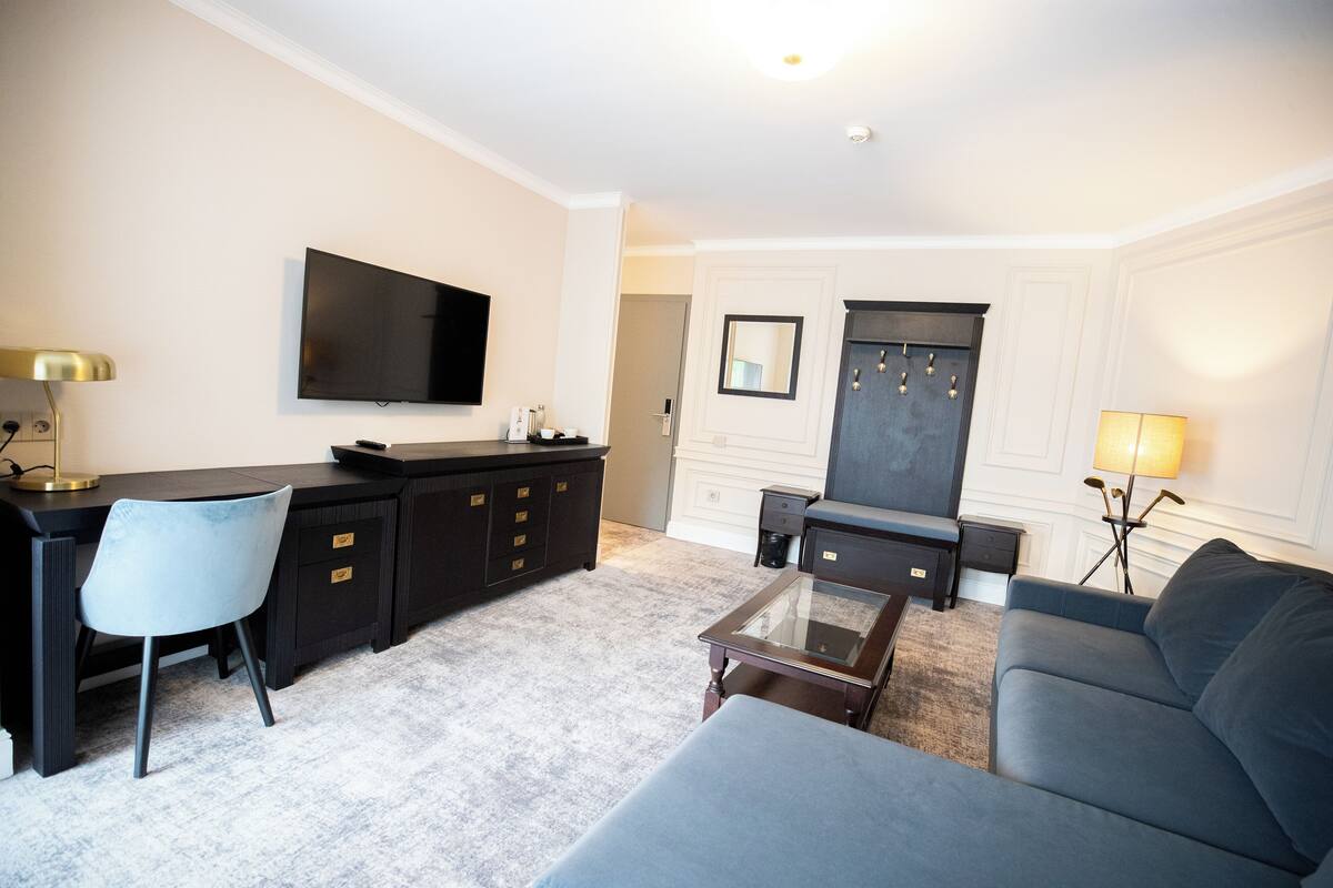 Una sala de estar moderna con un televisor de pantalla plana, un sofá, una mesa de centro y un escritorio con una silla.