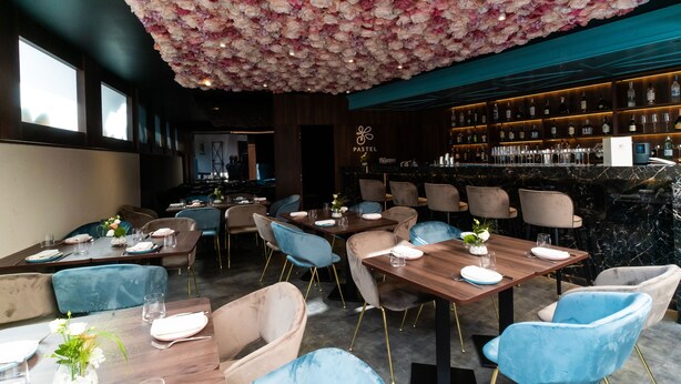 A restaurant with a ceiling covered in flowers, wooden tables, and blue chairs. - Hotel Meridian (Cluj-Napoca)