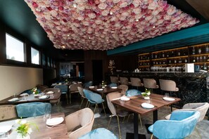 Un restaurant dont le plafond est recouvert de fleurs, avec des tables en bois et des chaises bleues.