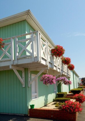 Un bâtiment écologique doté d’un balcon blanc et de jardinières suspendues.