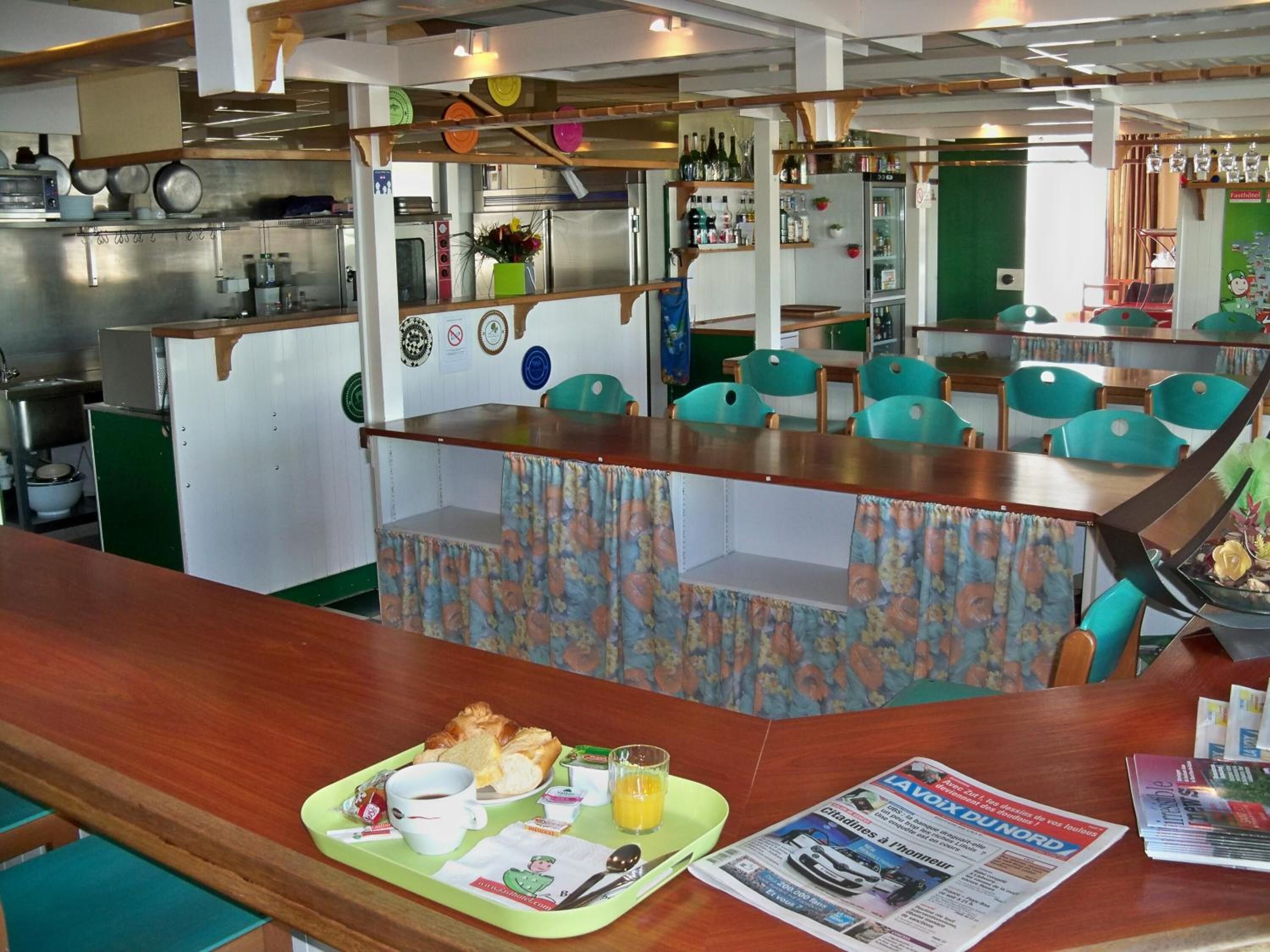 A restaurant with a counter, chairs, and a table with breakfast items.