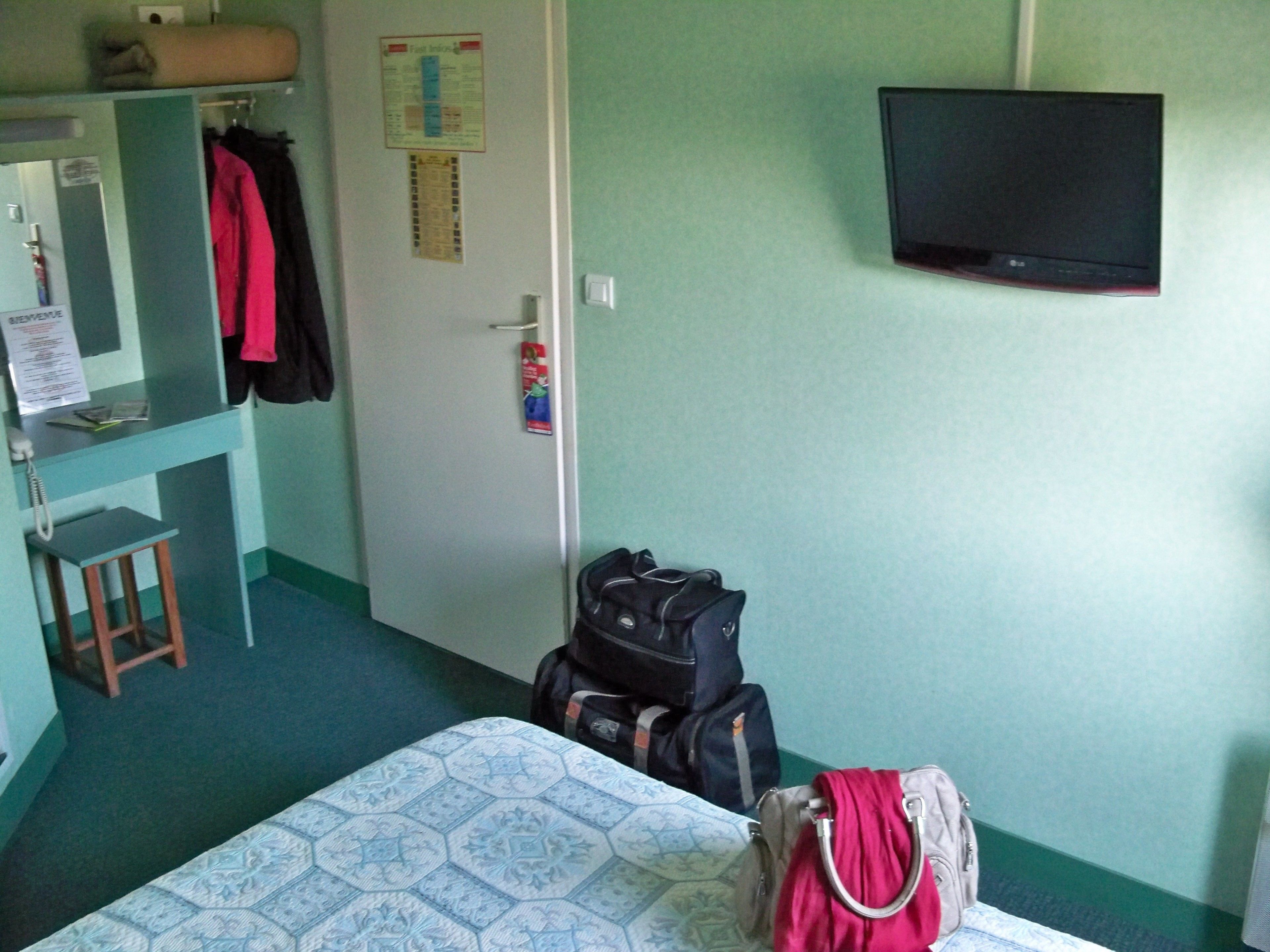 Une chambre comprenant un lit, un bureau, une chaise, une télévision et une armoire.