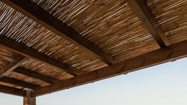 A hot tub under a wooden pergola with a desert view.
