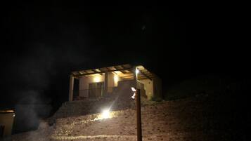 A building with a stone exterior and a lit entrance at night.