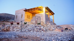 A modern house with a stone facade, a wooden pergola, and a staircase leading to the entrance.