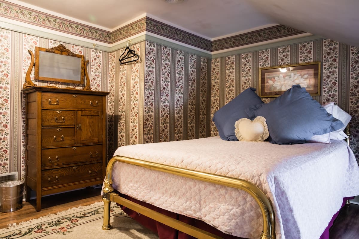 A bedroom with a bed, dresser, and a framed picture on the wall.