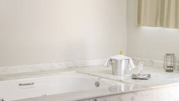 A bathroom with a marble sink, a bathtub, and a glass on the counter.