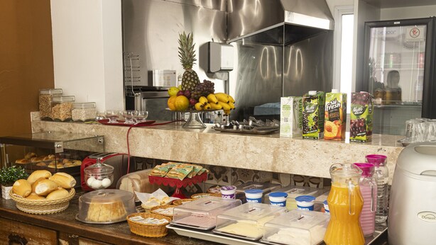 A buffet counter with various food items, including fruits, bread, and beverages.