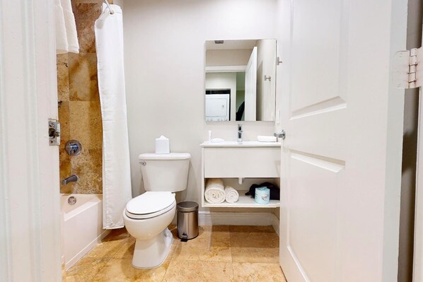 A compact bathroom with a toilet, sink, and bathtub. - Nuvo Suites Hotel (Miami)