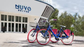 Zwei Fahrräder mit roten Reifen stehen vor einem Gebäude, an dem ein Schild mit der Aufschrift "NUVO SUITES" angebracht ist.