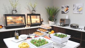 Un buffet proposant une variété de plats, notamment des pâtisseries, des salades et des fruits.