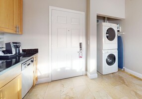 Una cocina funcional con lavavajillas, una puerta blanca y lavadora y secadora apiladas.