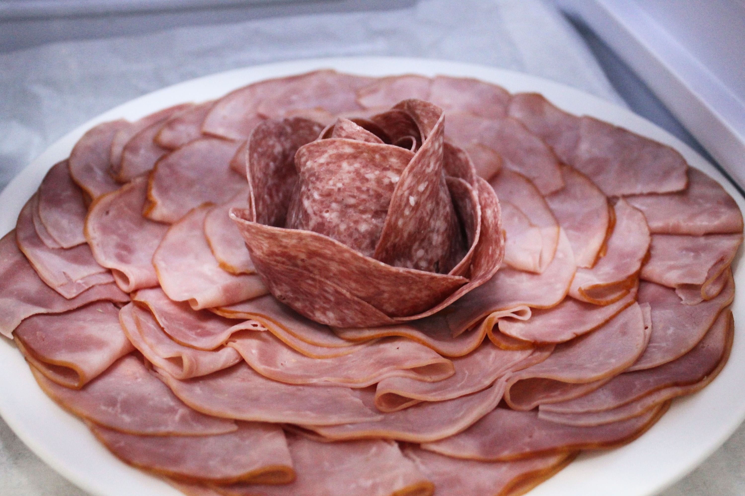 A plate of sliced meats arranged in a circular pattern with a central piece of meat.
