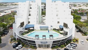 Un hôtel moderne doté d’une piscine centrale, de plusieurs étages et d’un parking.