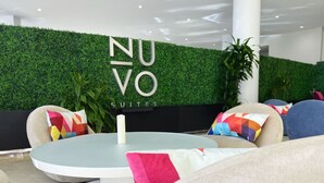 Un hall d’hôtel moderne agrémenté d’un mur végétal, de tables rondes et de coussins aux couleurs vives.