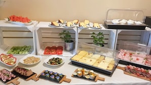 A buffet with various food items including sliced cucumbers, tomatoes, salads, and meat. - Confero (Nysa)