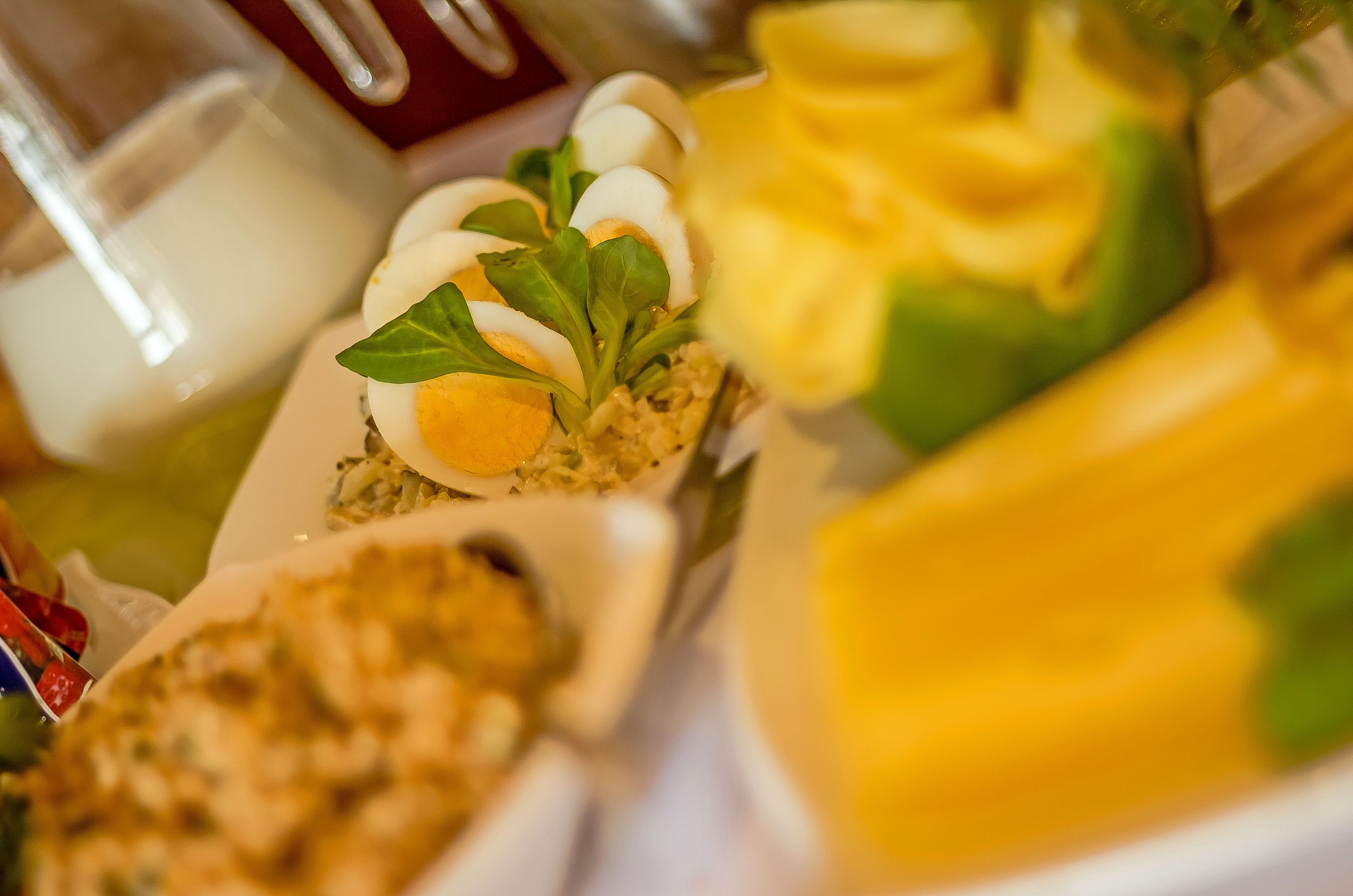 A close-up of various food items on a table, including sliced eggs, greens, and a yellow dish.