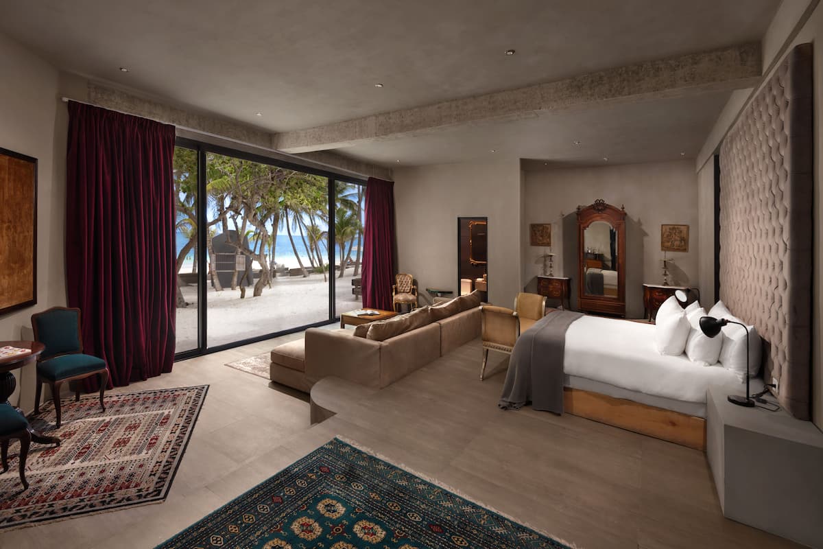Une chambre d’hôtel moderne dotée d’un grand lit, d’un canapé, d’un bureau et offrant une vue sur la plage.