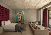 A modern bedroom with a large bed, a sofa, and a painting on the wall.