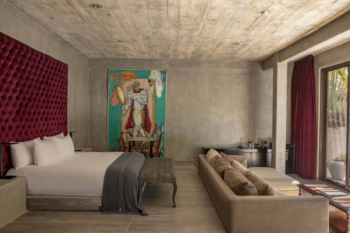 Une chambre moderne avec un grand lit, un canapé et un tableau au mur.