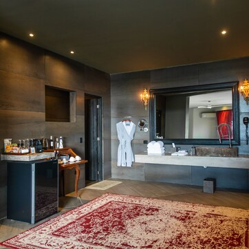 A modern bathroom with a large mirror, a vanity, and a red rug.
