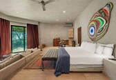 A modern bedroom with a large bed, a seating area, and a view of the outdoors.