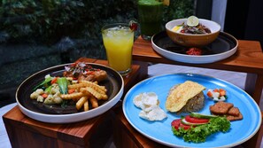Une table avec trois plats : un bol de riz aux légumes, une assiette de riz et de viande, et une assiette de plats frits et de légumes.