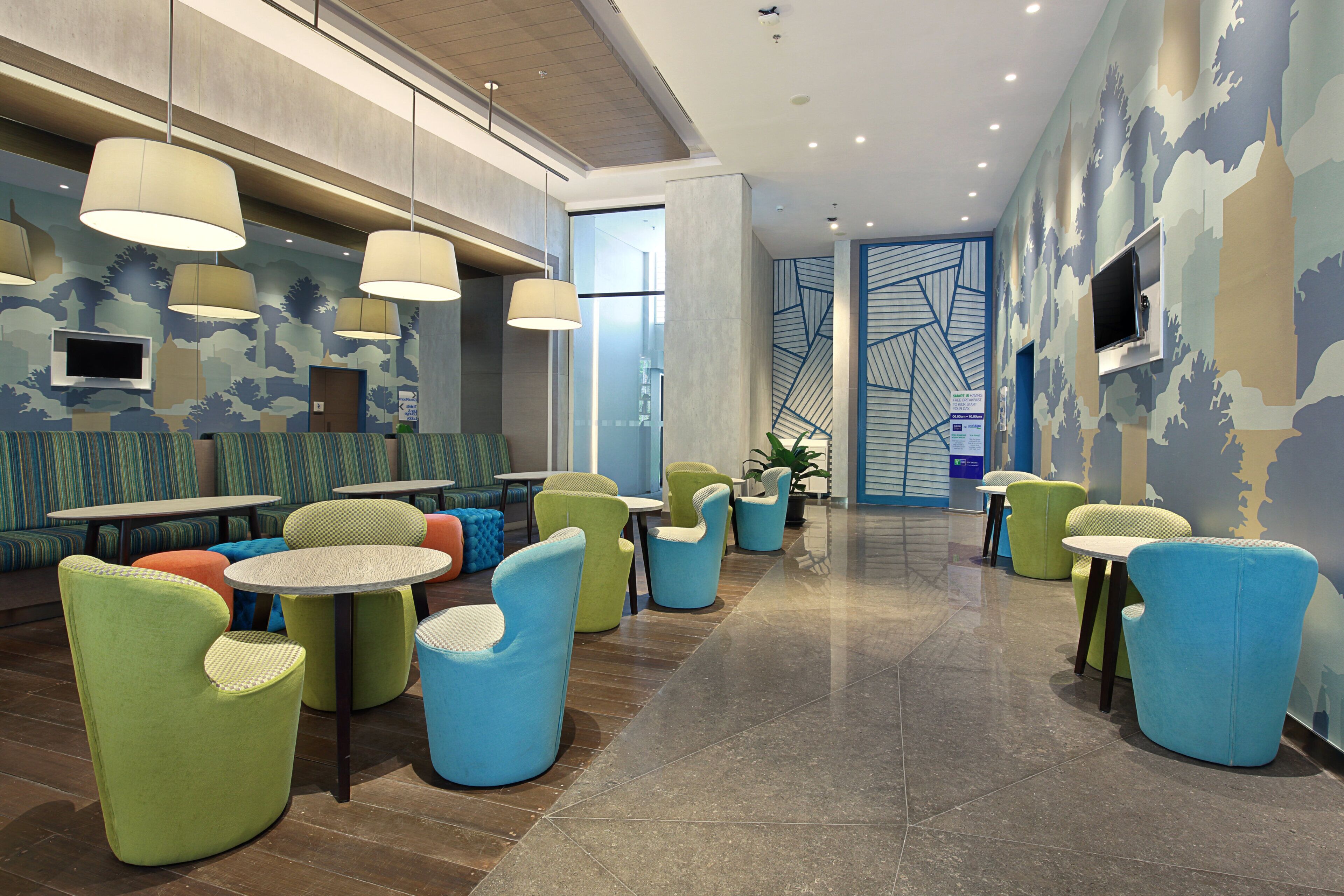 A modern lobby with seating areas, a television, and a patterned wall.