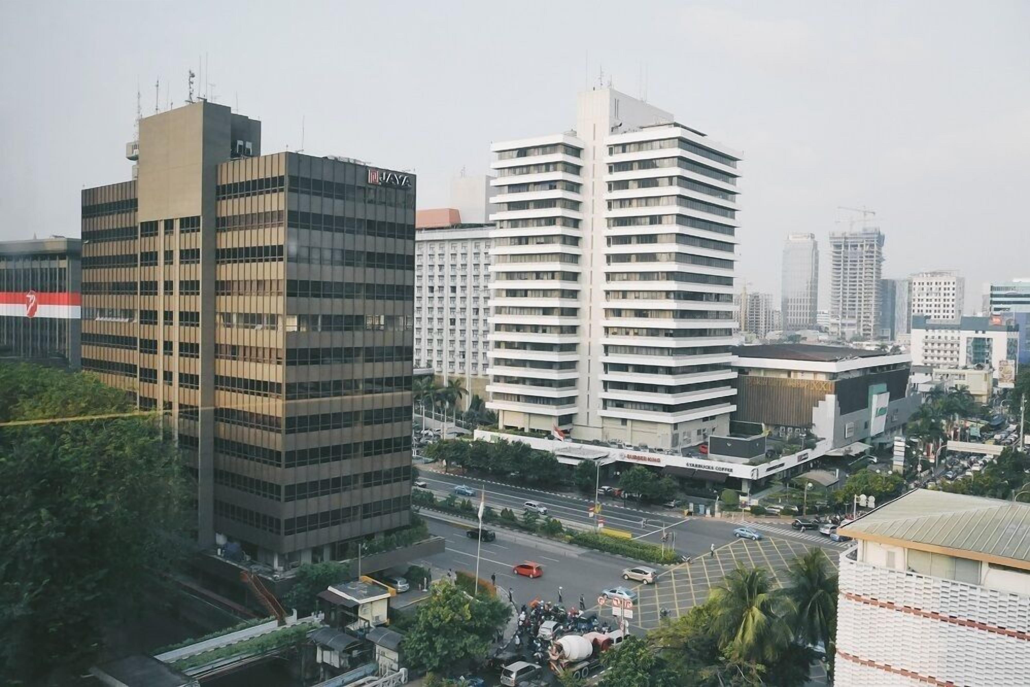 A cityscape with modern buildings, a Starbucks, and a busy street.
