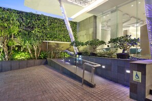 An outdoor area with a glass railing, a potted plant, and a sign indicating accessibility. - Holiday Inn Express Jakarta Wahid Hasyim by IHG (Jakarta)