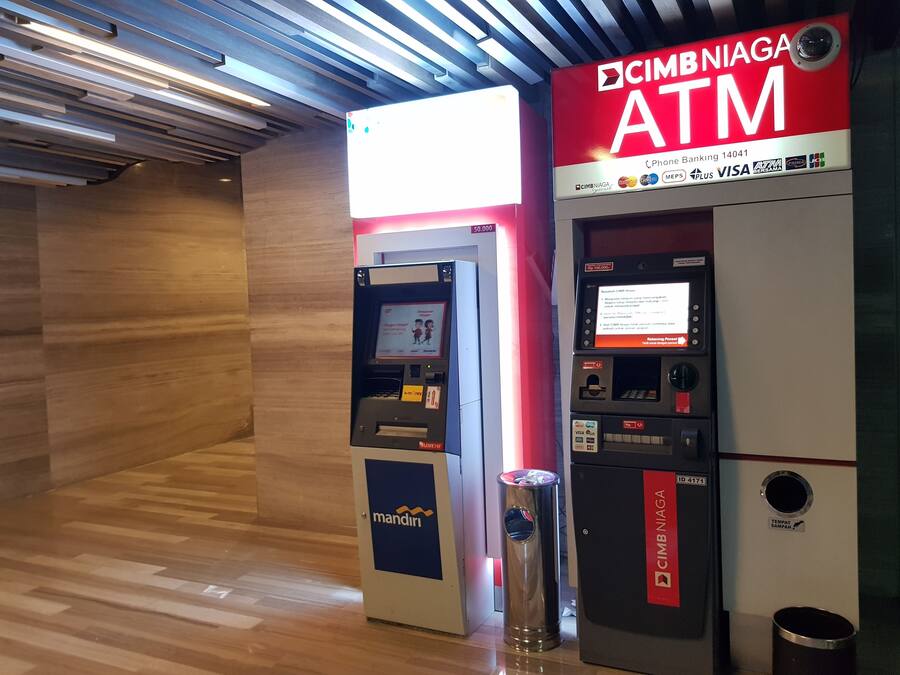 An ATM machine with a red and white sign, a 'mandiri' logo, and a 'CIMB NIAGA' label.